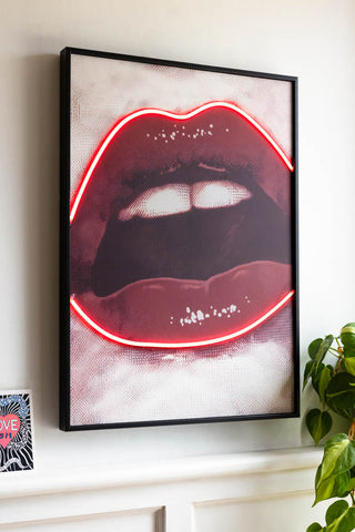 The Bold Red Lip Neon Wall Art shown hung on a white wall with the neon lips outline on. 