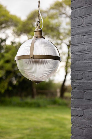 Lifestyle image of the Boulevard Pendant Light hanging in a garden.
