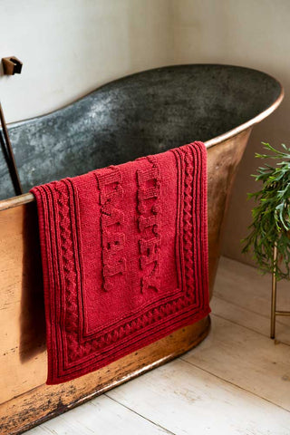 Image showing the Filthy Animal Cherry Red Bath Mat draped over a copper bath. 