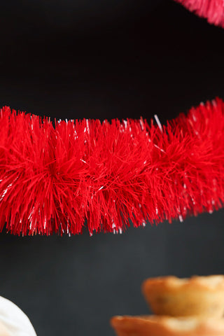 Close-up of the Bright Red Tinsel in front of a dark background.