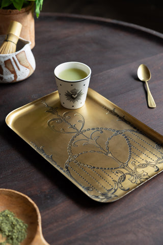 The Brushed Gold Art Nouveau Tray styled with a cup of matcha on, surrounded by other kitchen accessories and a potted plant.