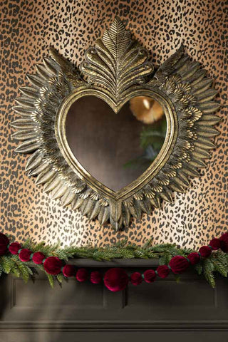 The Burgundy Velvet Sphere Christmas Garland styled with some greenery beneath a large heart mirror on the wall.