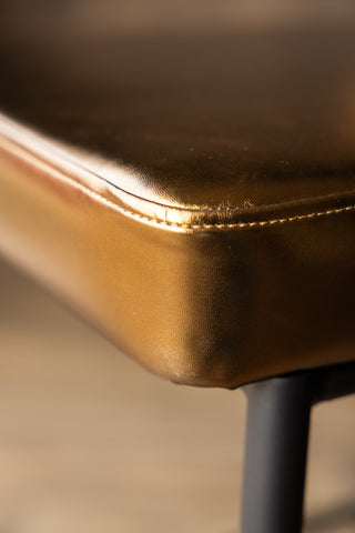Close-up image of the corner of the Burnished Gold Roll Back Bar Stool