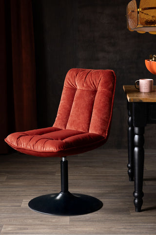 The Burnt Orange Velvet Swivel Dining Chair styled next to a dining table.