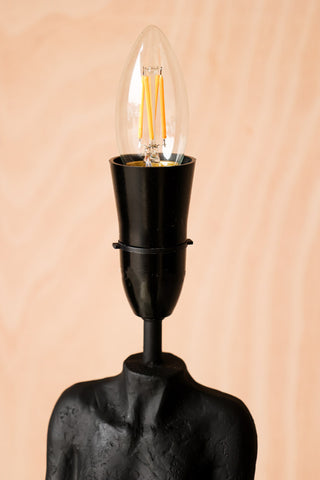 Lifestyle image of the Candle B22 4W Clear LED Light Bulb on a black lamp. 