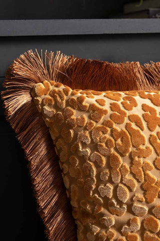Close-up of the corner of the Ochre Leopard Velvet Cushion with Fringe Trim.
