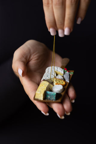 The The Cheese Board Christmas Decoration shown being held. 