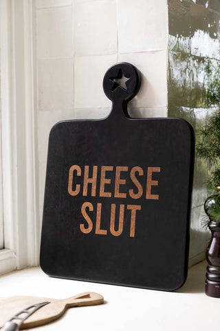 The Cheese Slut Square Wooden Serving Board shown in a kitchen against white zellige tiles. 