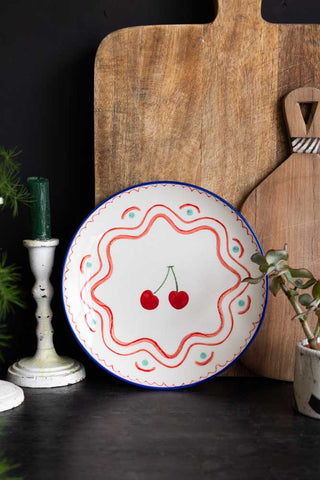 The Cherry Print Ceramic Serving Plate leaning against chopping boards.