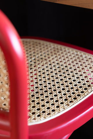 Close-up of the cane seat of the Chez Pitou Wood & Woven Cane Bar Stool in Red.