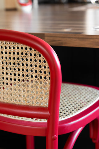 Close-up of the back of the Chez Pitou Wood & Woven Cane Bar Stool in Red.