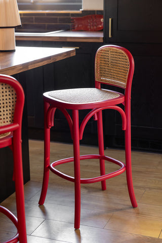 Two of the Chez Pitou Wood & Woven Cane Bar Stool in Red styled in a kitchen next to a kitchen island.
