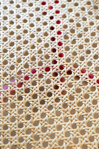 Detail shot of the cane on the seat of the Chez Pitou Wood & Woven Cane Bar Stool in Red.
