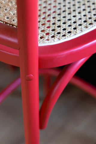 Close-up of the red of the Chez Pitou Wood & Woven Cane Bar Stool in Red.