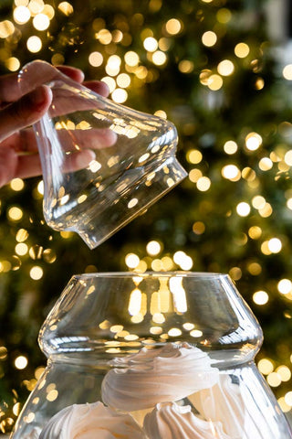 The Christmas Tree Glass Storage Jar with the lid off, held in a model's hands.