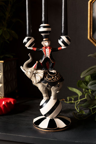 The Circus Animal Acrobat Candelabra on a dark wooden sideboard with a plant and various accessories.