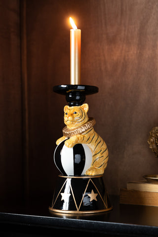 The Circus Tiger Candlestick Holder with a lit candle inside, styled on a dark surface.