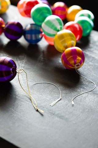 Close-up of the ends of the Colourful Thread Bauble Christmas Garland, displayed on a dark surface.