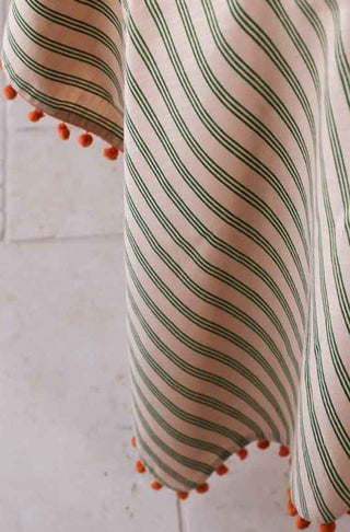 Detail of the lifestyle for the Cotton Green Stripe Table Cloth with Orange Pom-Poms