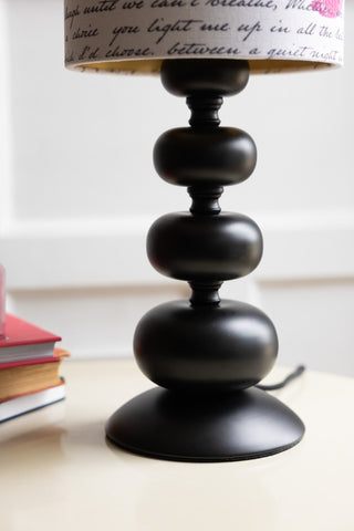 Detail shot of the curved bobbin base of the Curve Black Table Lamp With Love Letter Shade. 