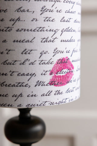 A detail shot of the pink lipstick kiss marks on the pattern of the lampshade of the Curve Black Table Lamp With Love Letter Shade.
