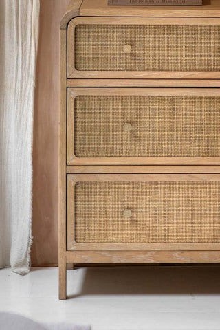 Close-up of the front of the Curved Wood & Rattan Chest Of Drawers, displayed in front of a wall with a curtain.