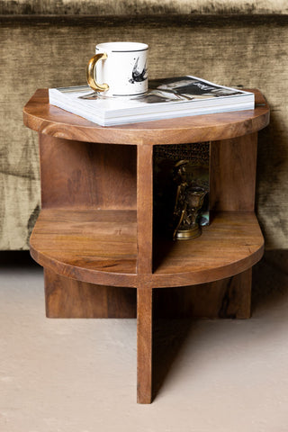 A head on view of the Dark Wood Shelf Side Table against a green sofa