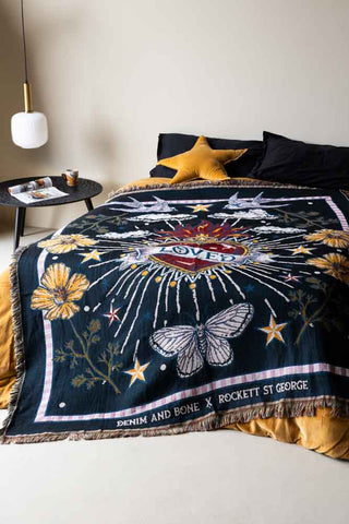 Dark midnight blue throw with tassels, a red heart, butterflies, stars and florals on a bed
