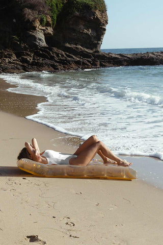 Lifestyle image of the Disco Gold Inflatable Pool Lilo on the beach