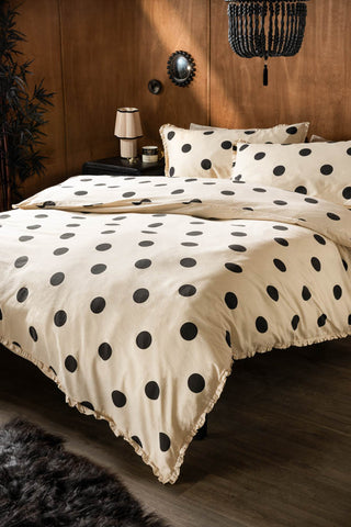 Dot Noir Ruffled Bedding Set styled against a wood wall with black accessories