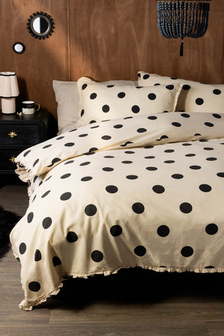 Dot Noir Ruffled Bedding Set styled against a textured wood wall with a black bedside table 
