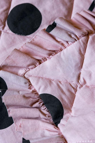 A detail image of the Dot Noir Ruffled  Bedspread, showing the ruffled edge of the quilt. 