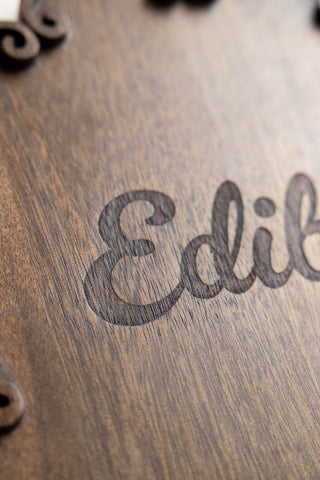 The etched text detail on the Edibles Scalloped Wooden Serving Board.