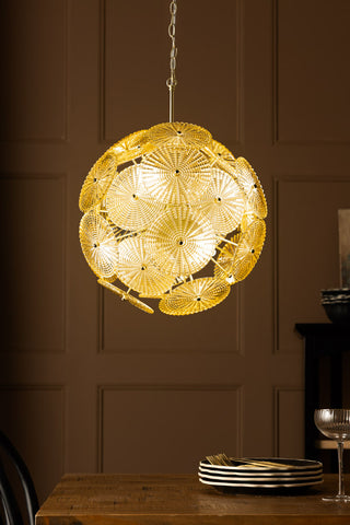 The Elegant Frosted Amber Leaf Ceiling Light switched on and hanging above a dining table.