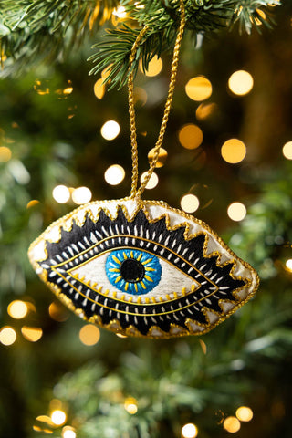 The Embroidered Blue Eye Hanging Christmas Tree Decoration hanging from the branch of a Christmas tree.