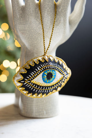 The Embroidered Blue Eye Hanging Christmas Tree Decoration hanging from a ceramic statue.