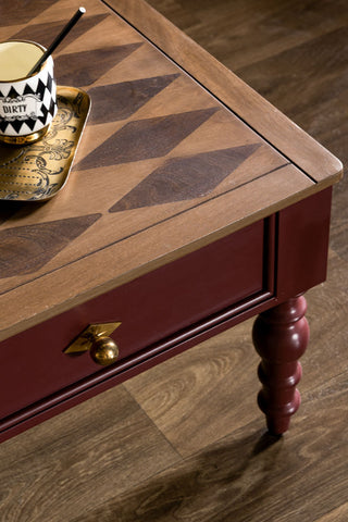 Detail of the Emporium Brick Red Coffee Table, showing the harlequin wood top and gold handles. 
