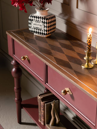 The Emporium Brick Red Console Table, shown from the side with a candle, and vase on top. 
