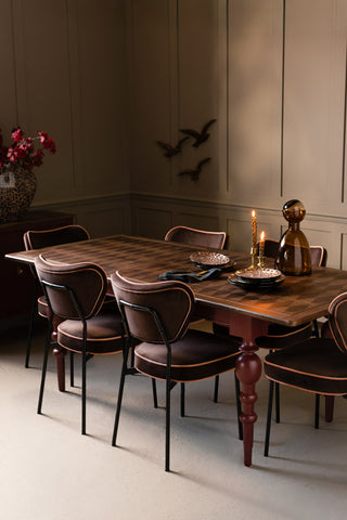 The Emporium Brick Red Extendable Dining Table, shown without the extension against beige panelled walls. 