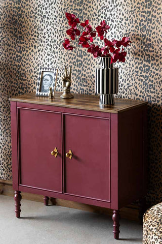 The Emporium Brick Red Sideboard styled with some accessories on in front of a leopard print wall.