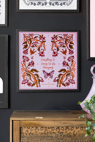 Framed artwork with floral design and motivational quote on a dark wall.