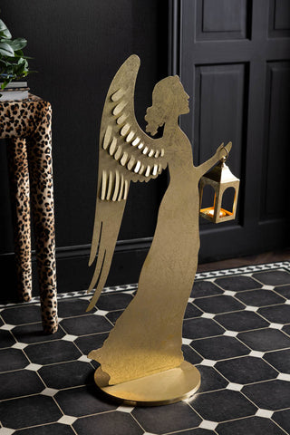 The Extra Large Gold Angel Decorative Lantern with a lit candle inside, styled in front of door/table.
