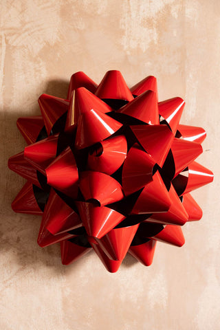 The Large Red Gift Bow Christmas Decoration styled on the wall.