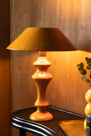 The Fabulous Enamel Mustard Gold Table Lamp switched on and styled on a console table with some other accessories.