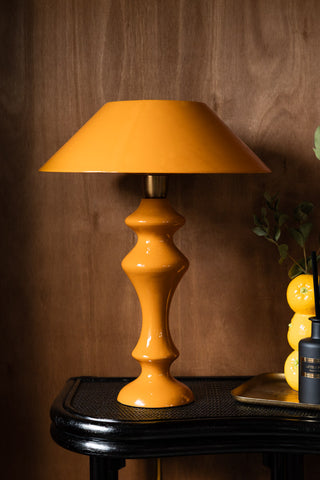 The Fabulous Enamel Mustard Gold Table Lamp displayed on a console table with some other accessories.