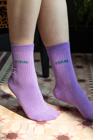 The Feral Cotton Glitter Socks shown on a model against a pink tile-effect floor. 