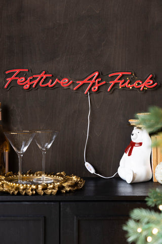 Decorative sign with 'Festive As F**k' on a dark background with Christmas decor.