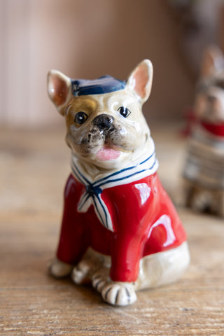 A Frenchie from the French Bulldog Salt & Pepper Shaker Set shown with a red jumper, stripe neck scarf and blue hat. 
