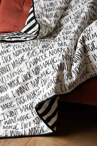 The Fuck Normal, I Want Magic Print Reversible Quilt displayed on a sofa.