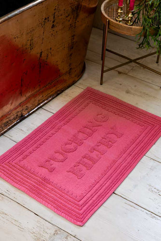 Fucking Filthy Hot Pink Bath Mat shown next to a copper bath. 